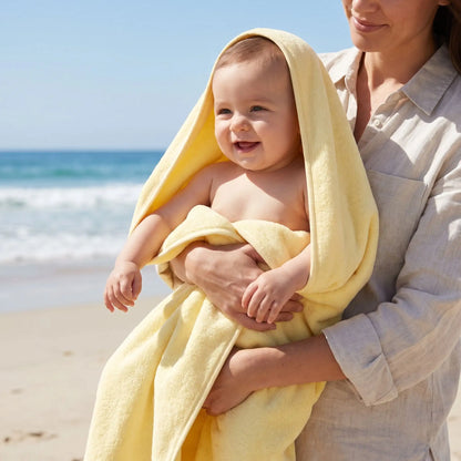 bébé dans les bras de maman souriant dans sa serviette jaune